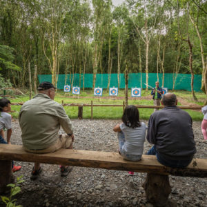Teaching Archery Man teaching bow and arrow to children
