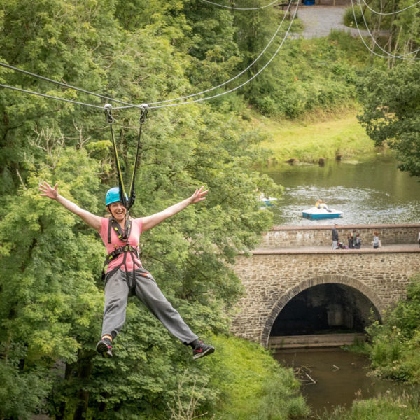 Zipline Woman ziplining over bridge and lake
