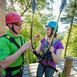 Man and women at the top of zipline in conversation.