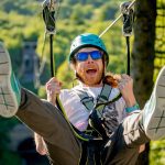 Man on zip line in the sunshine close up with feet up