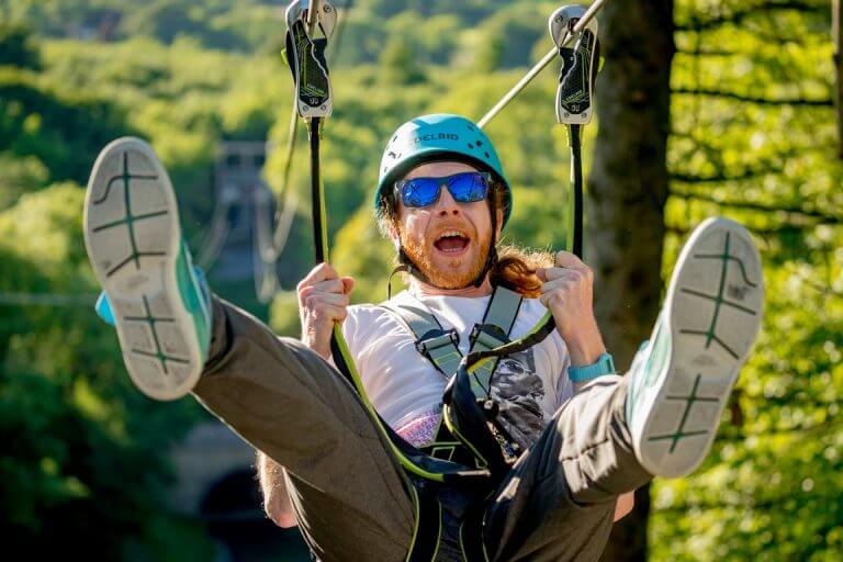 Man on zip line in the sunshine close up with feet up